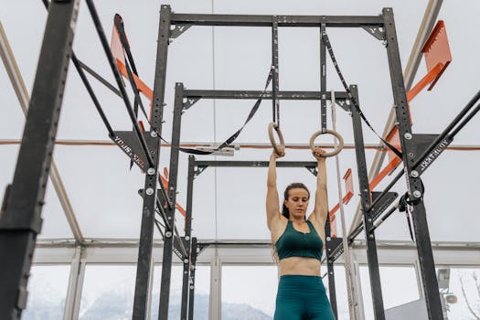 A woman training with gymnastics rings in a modern gym setup, focusing on fitness.