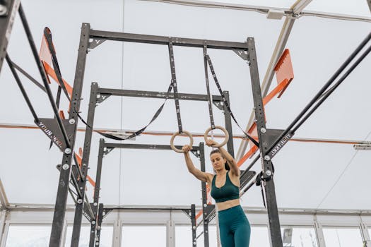 Woman exercising on gymnastic rings in a modern indoor gym setting.