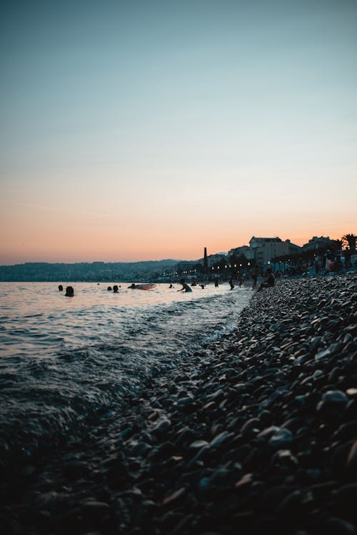 People Swimming in Sea at Dusk 