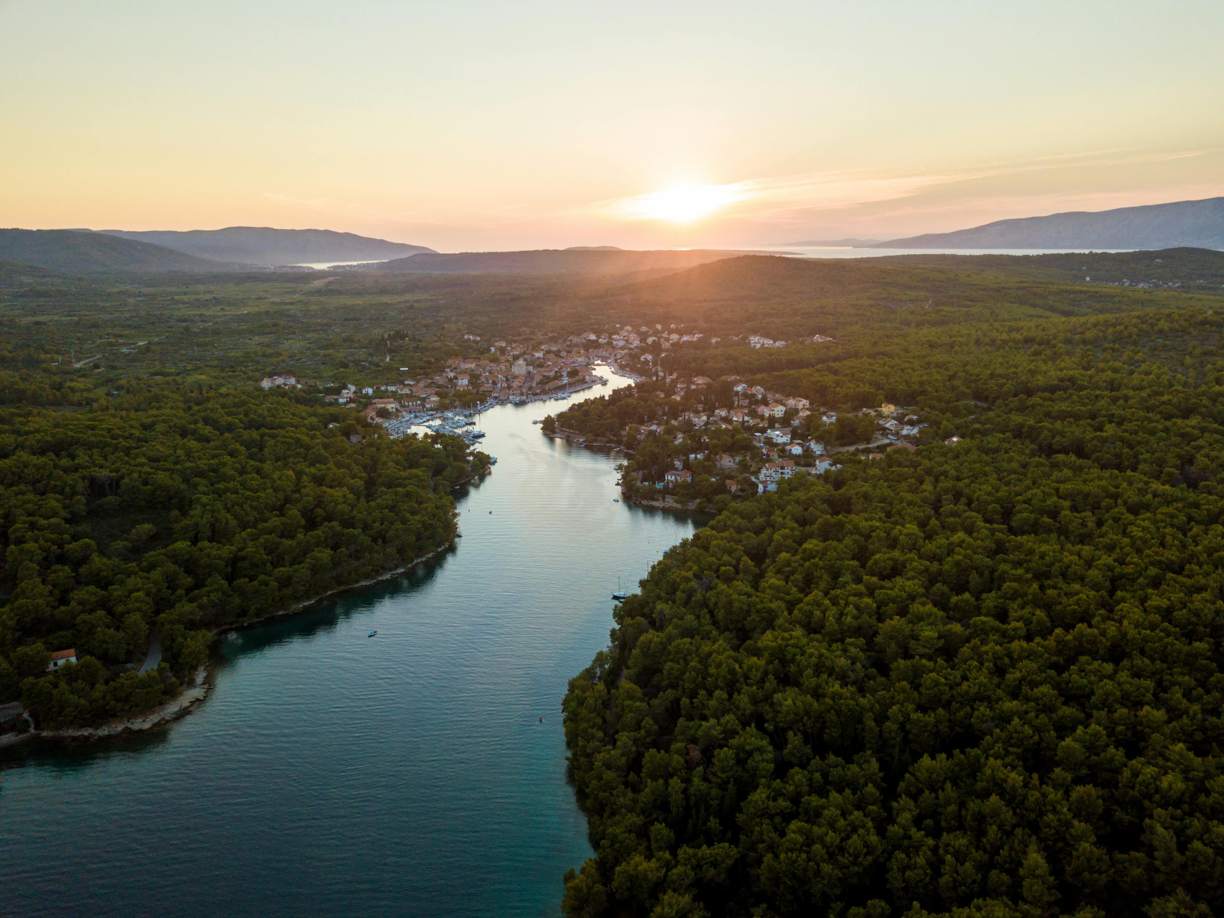 Stunning aerial view over Vrboska, Croatia, showcasing serene waters and lush forests at sunset.