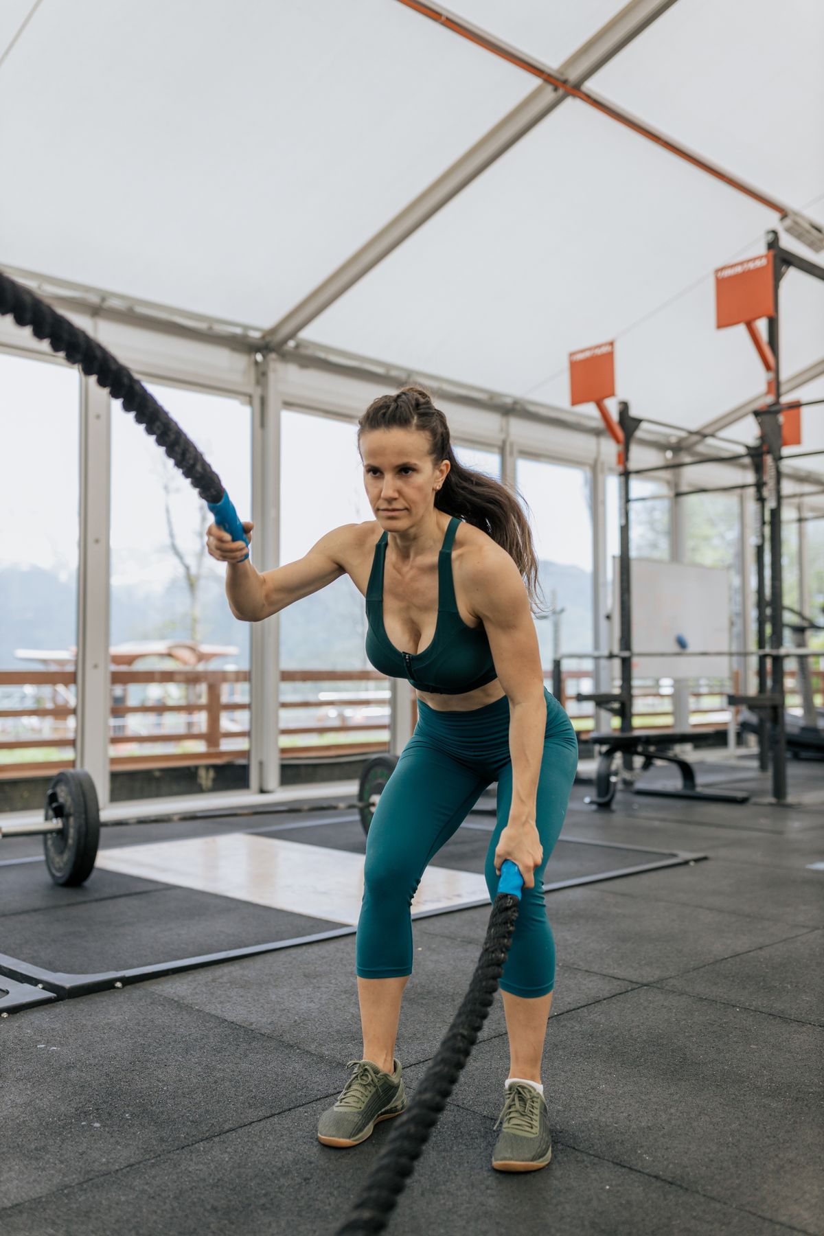Woman performing battle rope conditioning training in a gym