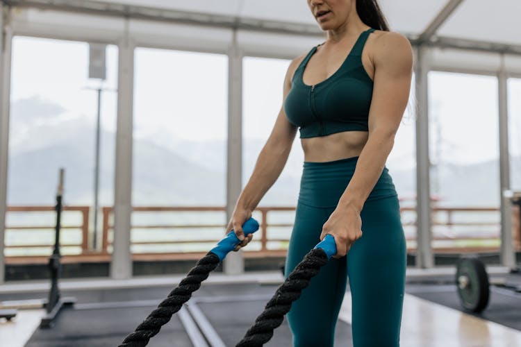 Woman In Green Activewear Gripping Thick Ropes