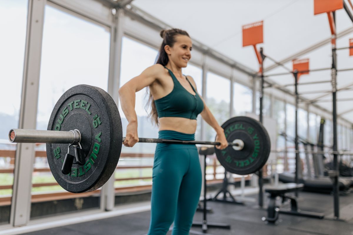 A woman lifting a loaded barbell during a gym session.