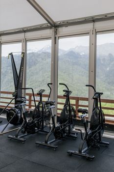 Indoor gym setup with stationary bikes facing scenic mountain views through large windows.