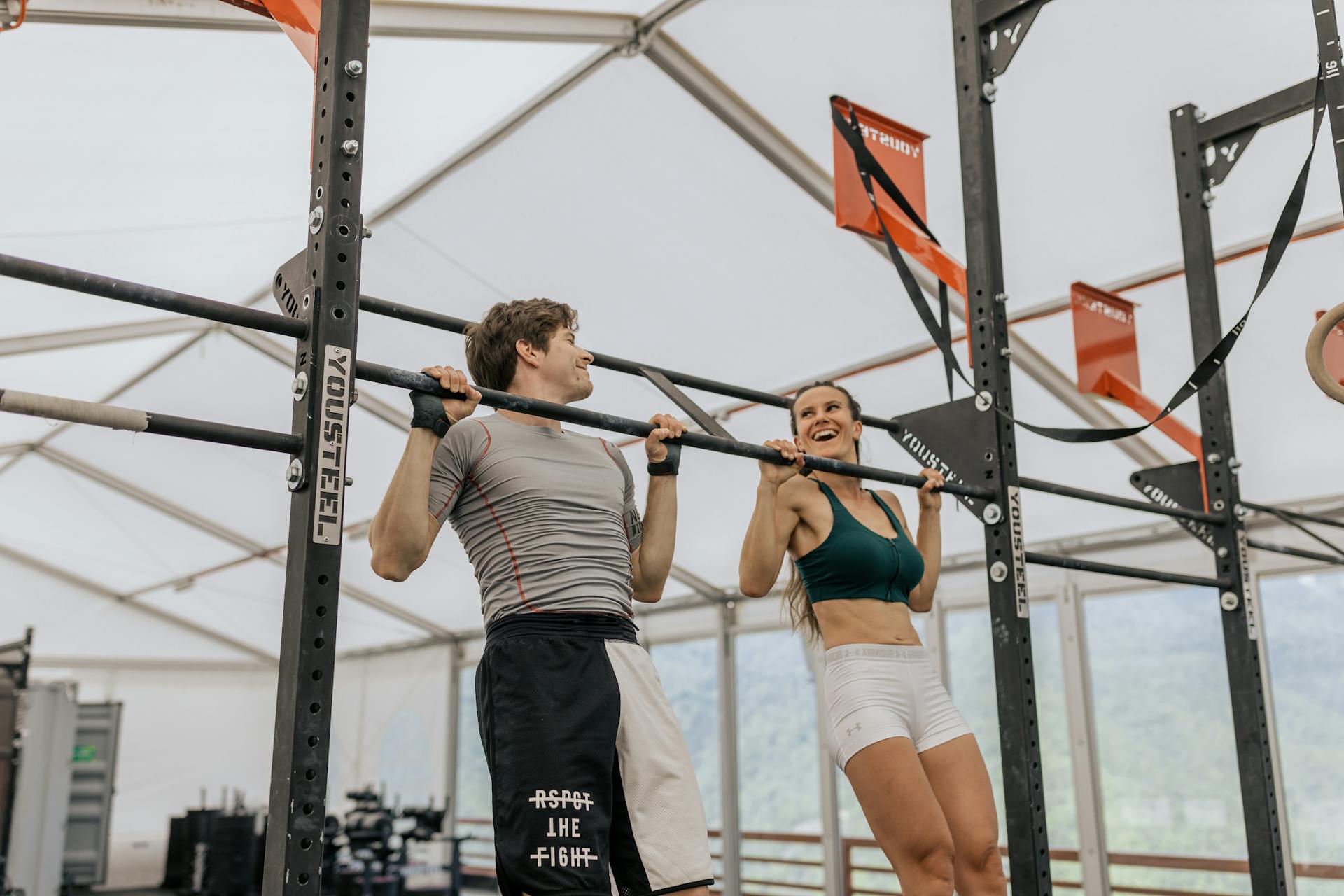Man and Woman Doing Pull Ups at the Gym