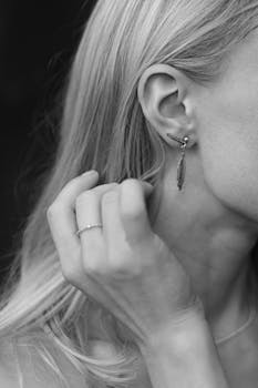 Close-up monochrome shot of a woman's ear adorned with stylish earrings, showcasing elegance.
