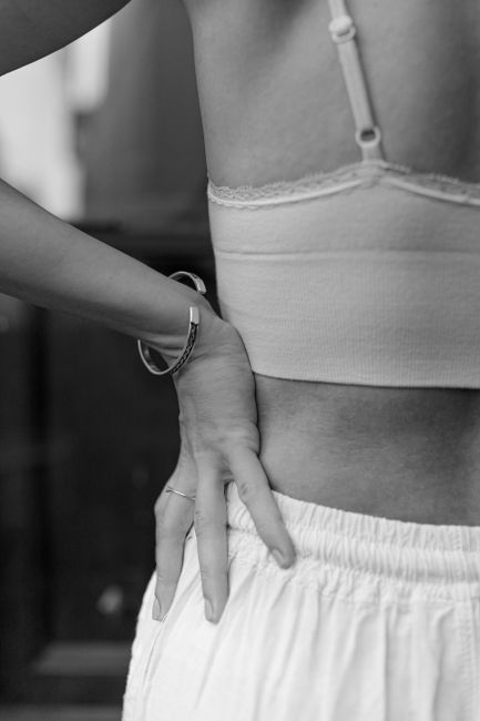 A black and white close-up of a woman's waist adorned with jewelry, creating a minimalist aesthetic.