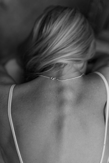 Artistic black and white photo capturing a woman's back wearing a necklace.