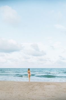 宁静的海滩上，一名女子独自站着，背景是广阔的海洋