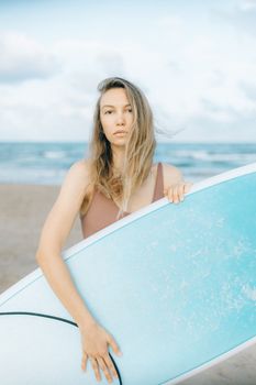 沙滩上，一名年轻女子拿着冲浪板，准备冲浪