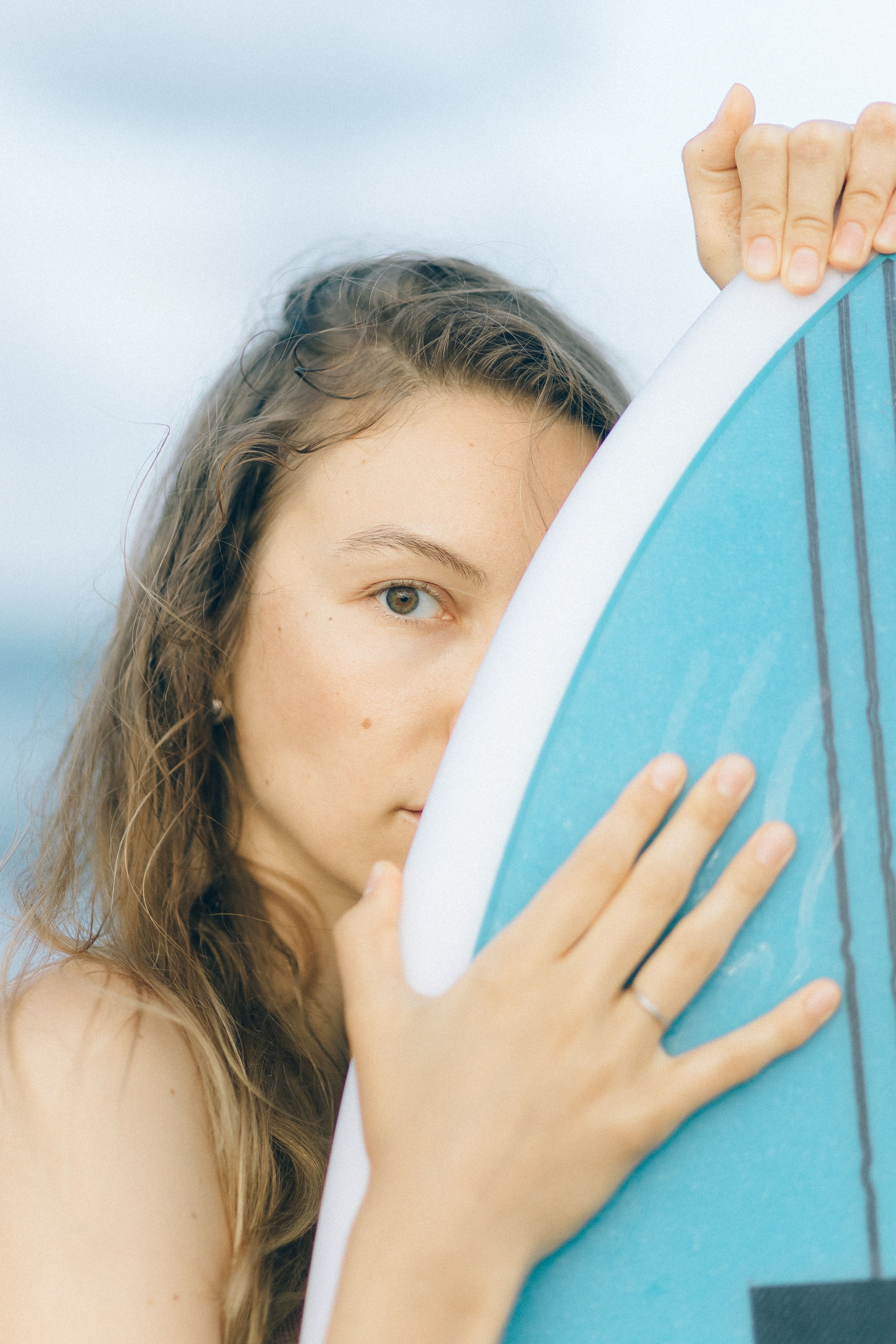 年轻女子在海滩上抱着冲浪板，洋溢着夏日气息