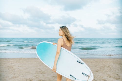 A Woman Carrying Surfboard on Beach