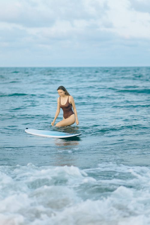 Woman in Brown Swimsuit Near a Surfboard