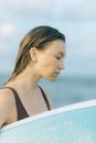 这张海滩上女士手持冲浪板的宁静画面，捕捉到一种轻松而沉思的心情