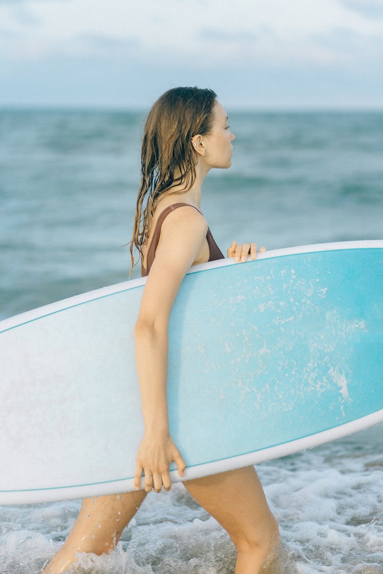 Woman Carrying Surfboard While Walking