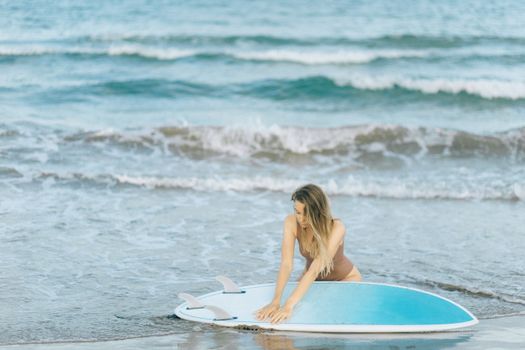 女人拿着冲浪板在海边享受阳光明媚的一天，完美的夏日氛围