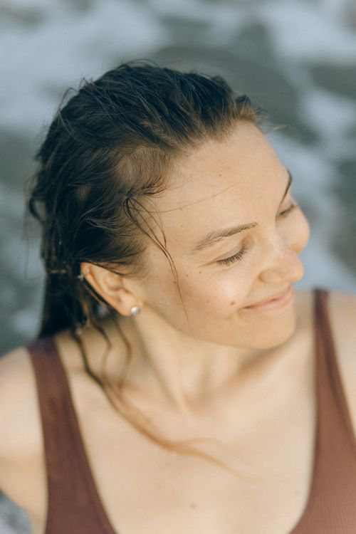 Free Portrait of a smiling woman at the beach, with wet hair and a relaxed expression. Stock Photo