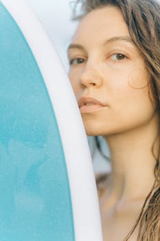Close-up portrait of a woman beside a surfboard, highlighting beach vibes and summer lifestyle.