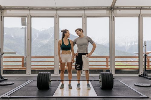 Free A couple in activewear standing together in a gym with weightlifting equipment. Stock Photo