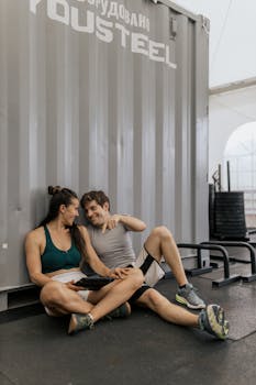 A couple in activewear relaxing and smiling indoors at a modern gym
