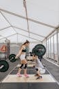 Man Lifting Barbell in Front of a Woman