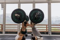 一对穿着运动服的夫妇在现代健身房里举起哑铃时接吻