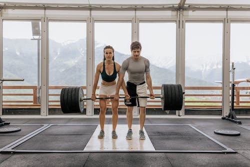 Free Man and Woman Lifting a Barbell Together Stock Photo