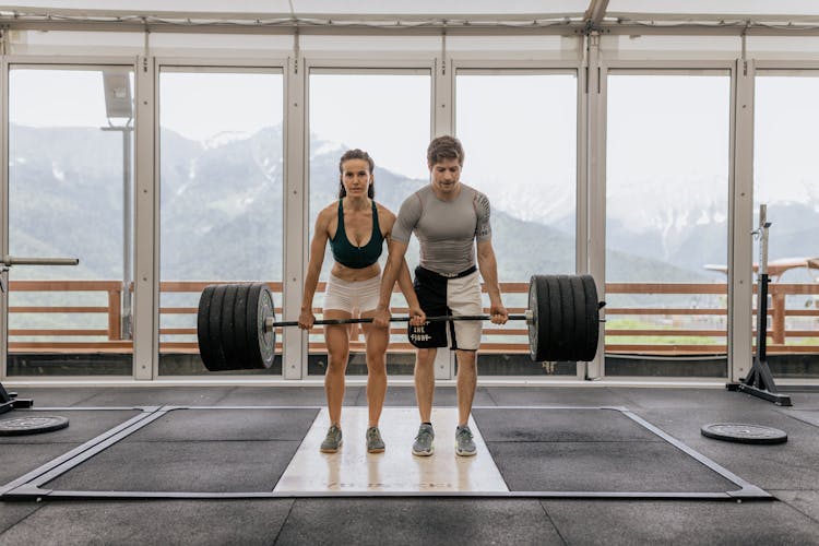 Man And Woman Lifting A Barbell Together