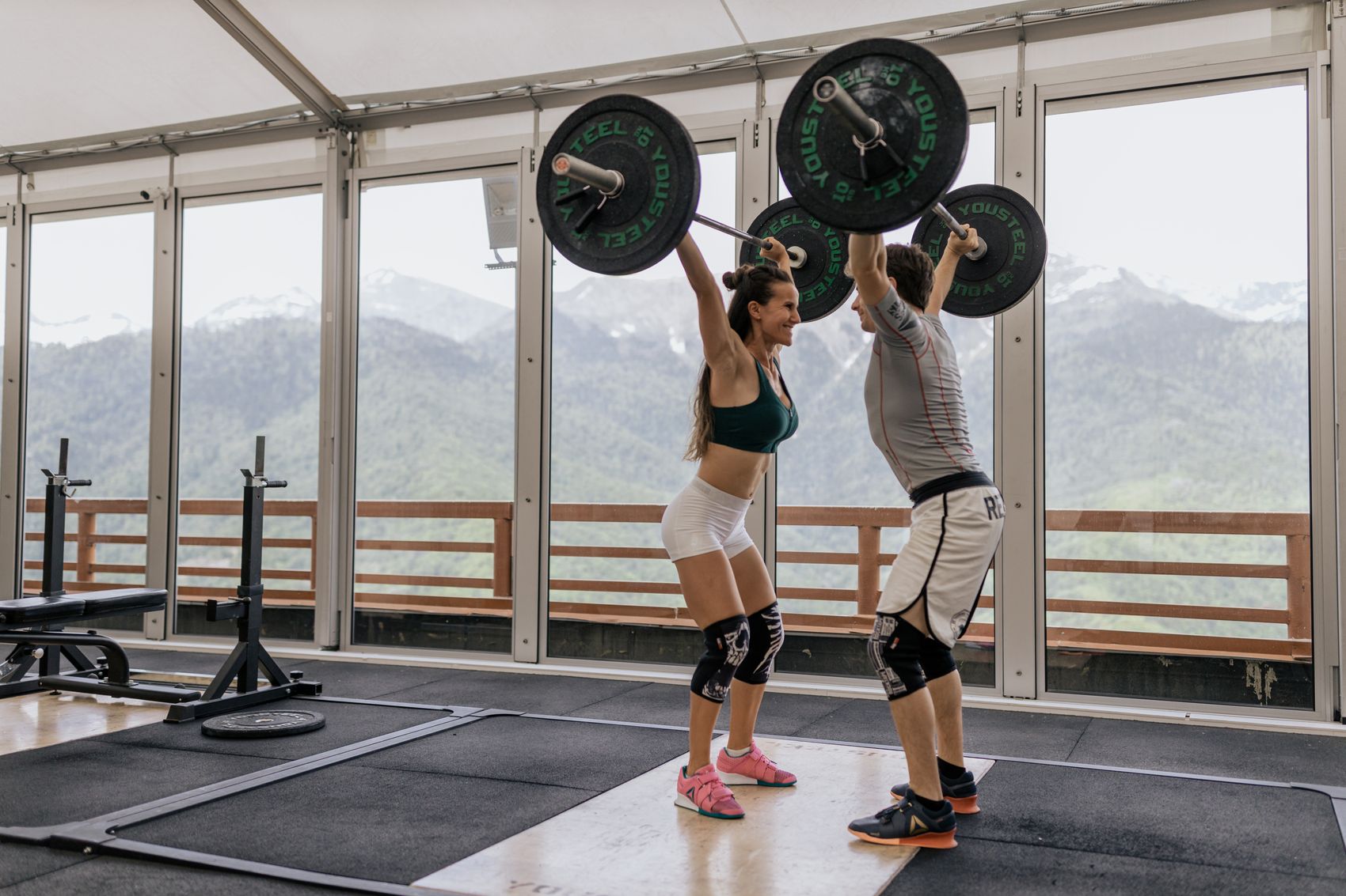 Training partners lifting barbells together during a gym workout
