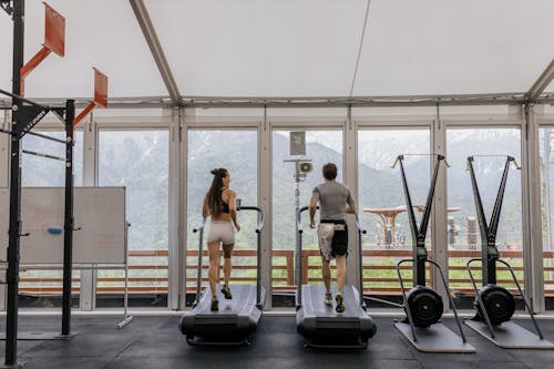 Man and Woman Exercising on a Treadmill at the Gym 