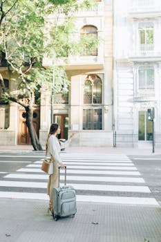 一名年轻女子提着行李箱，站在城市的人行横道上，指着前方