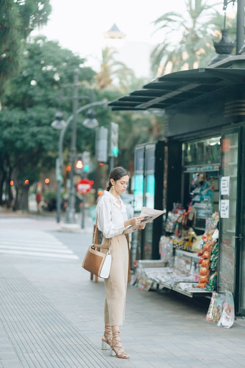 Stylish Woman Reading Newspaper on Sidewalk