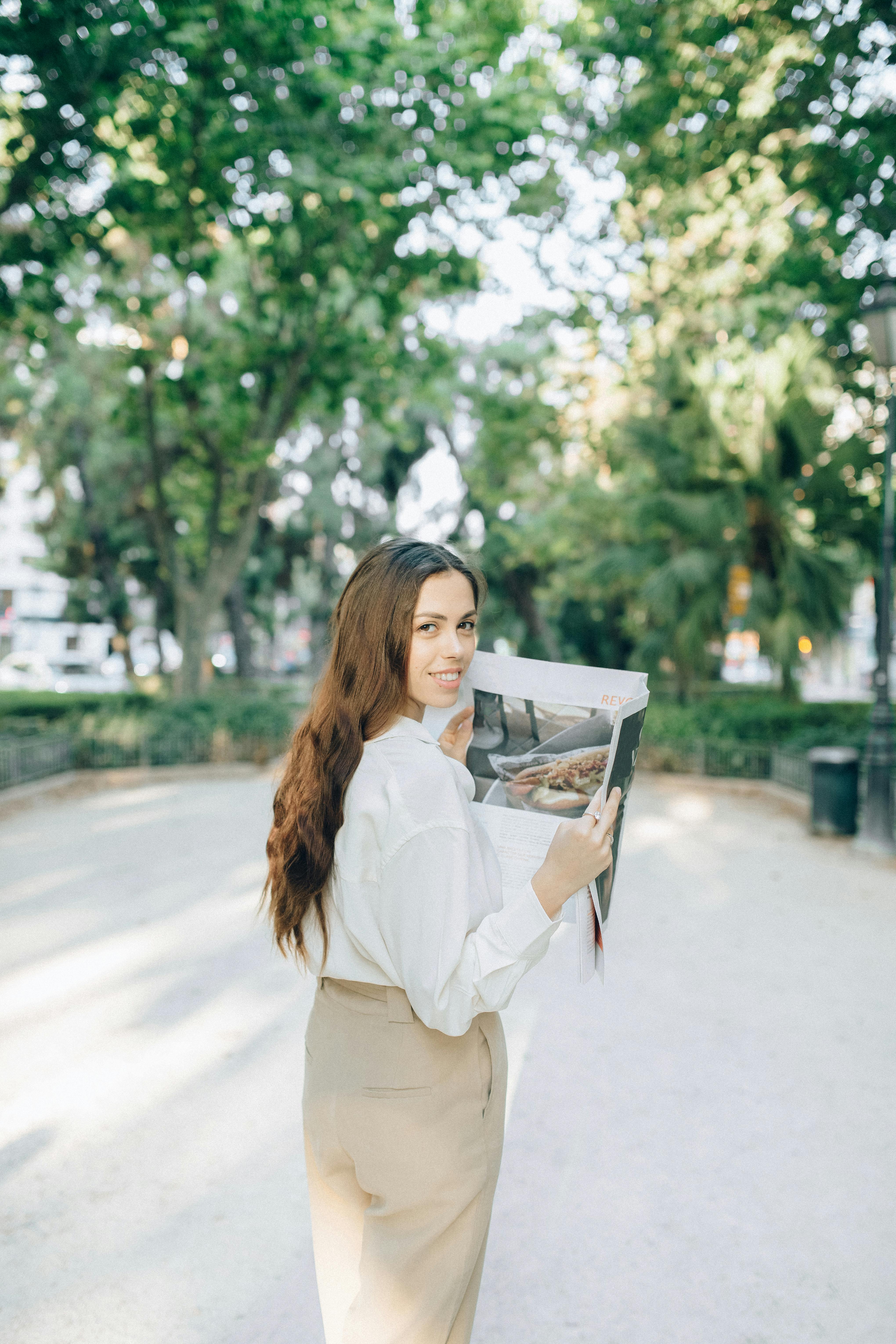 woman in white long sleeve shirt holding newspaper