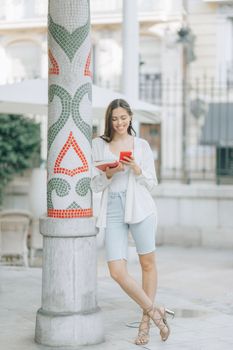 一名年轻女子穿着休闲服，在户外拿着手机享受休闲时光