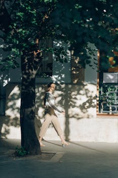 一位年轻女子在阳光明媚的城市街道上，沿着树影漫步，享受着这一天