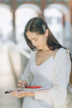 一位穿着休闲装的年轻女子在明亮的户外做笔记