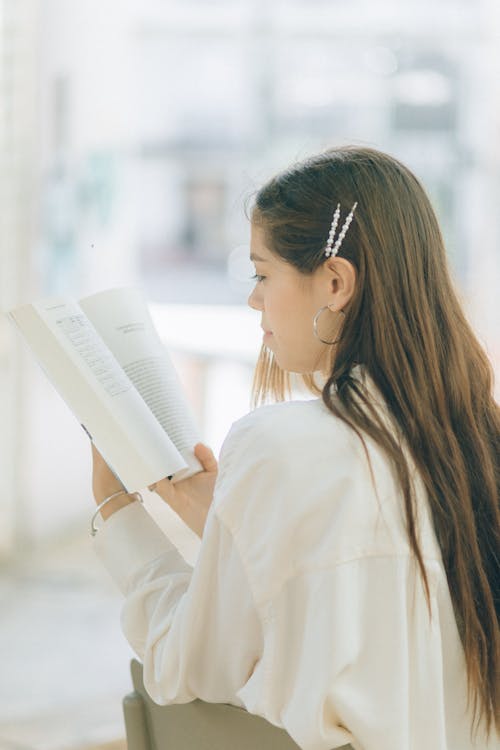 Woman in White Long Sleeve Shirt Reading a Book