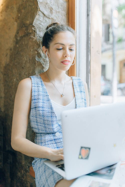 Woman Using a Laptop Beside a Window