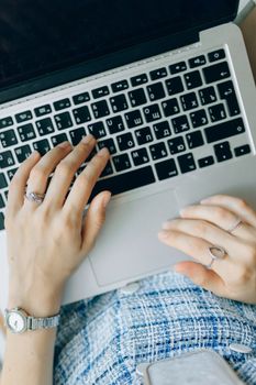 Close-up of a woman typing on a laptop with a Russian keyboard layout, wearing jewelry and a wristwatch.