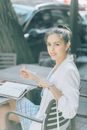 一位穿着职业装的自信女性在户外的咖啡桌上写作