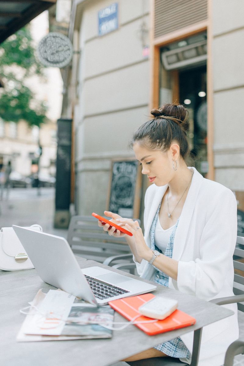 Working between a phone and a laptop at a desk — photo by Nataliya Vaitkevich on Pexels
