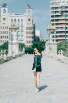 一位时髦的女人穿着时尚服装，在城市桥上一边漫步一边打电话