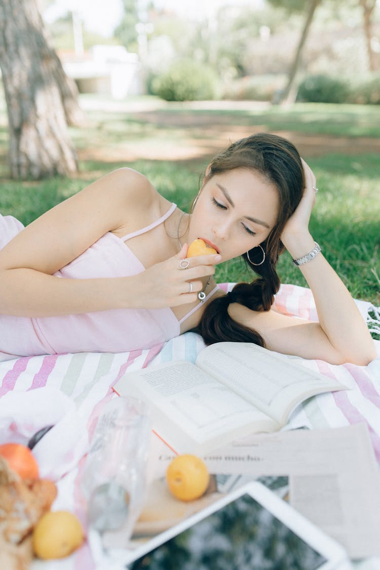 Woman Eating A Fruit While Reading