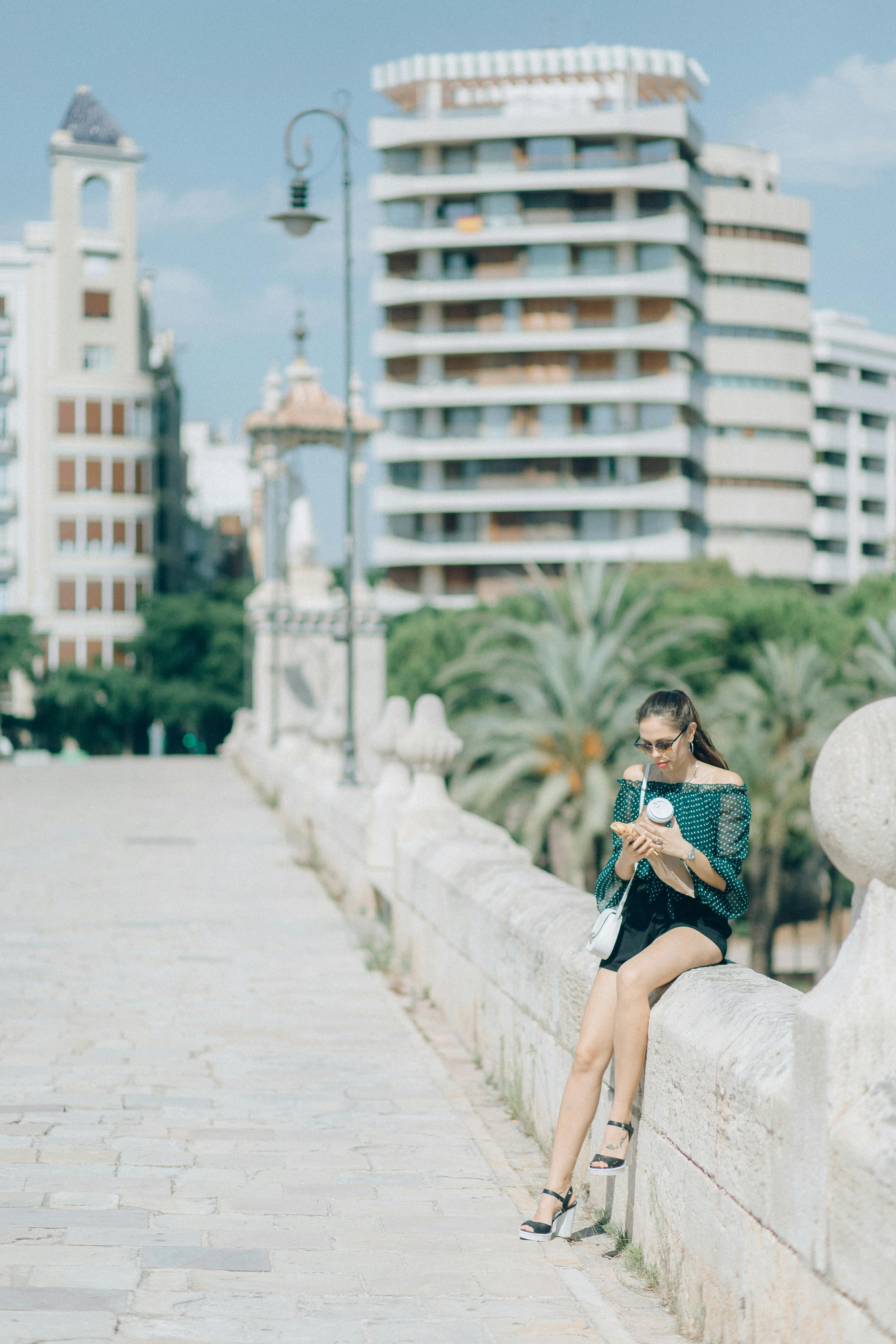 woman in black and white striped shirt and black shorts sitting on white concrete bench during