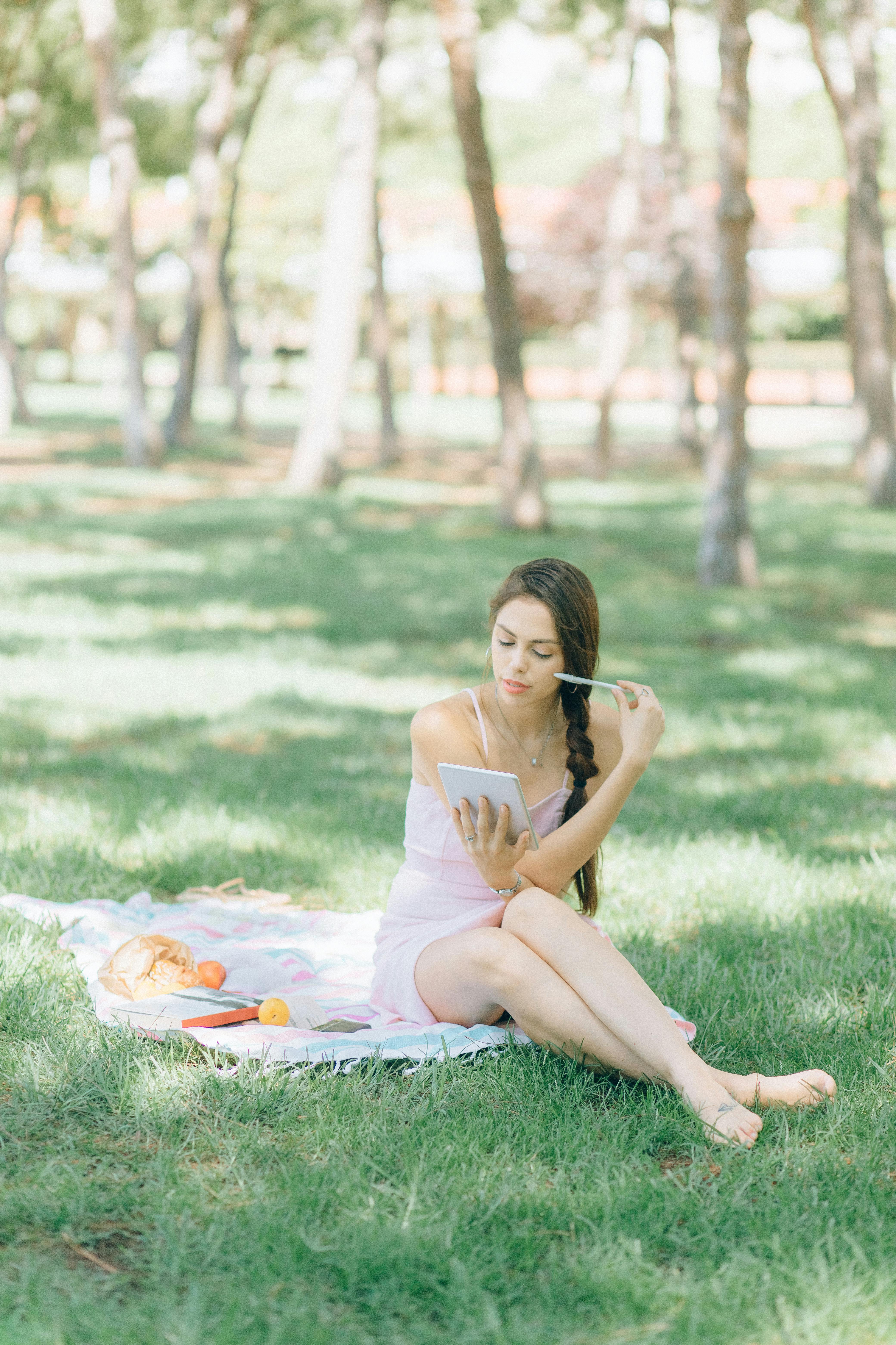 woman in white tank top sitting on green grass field