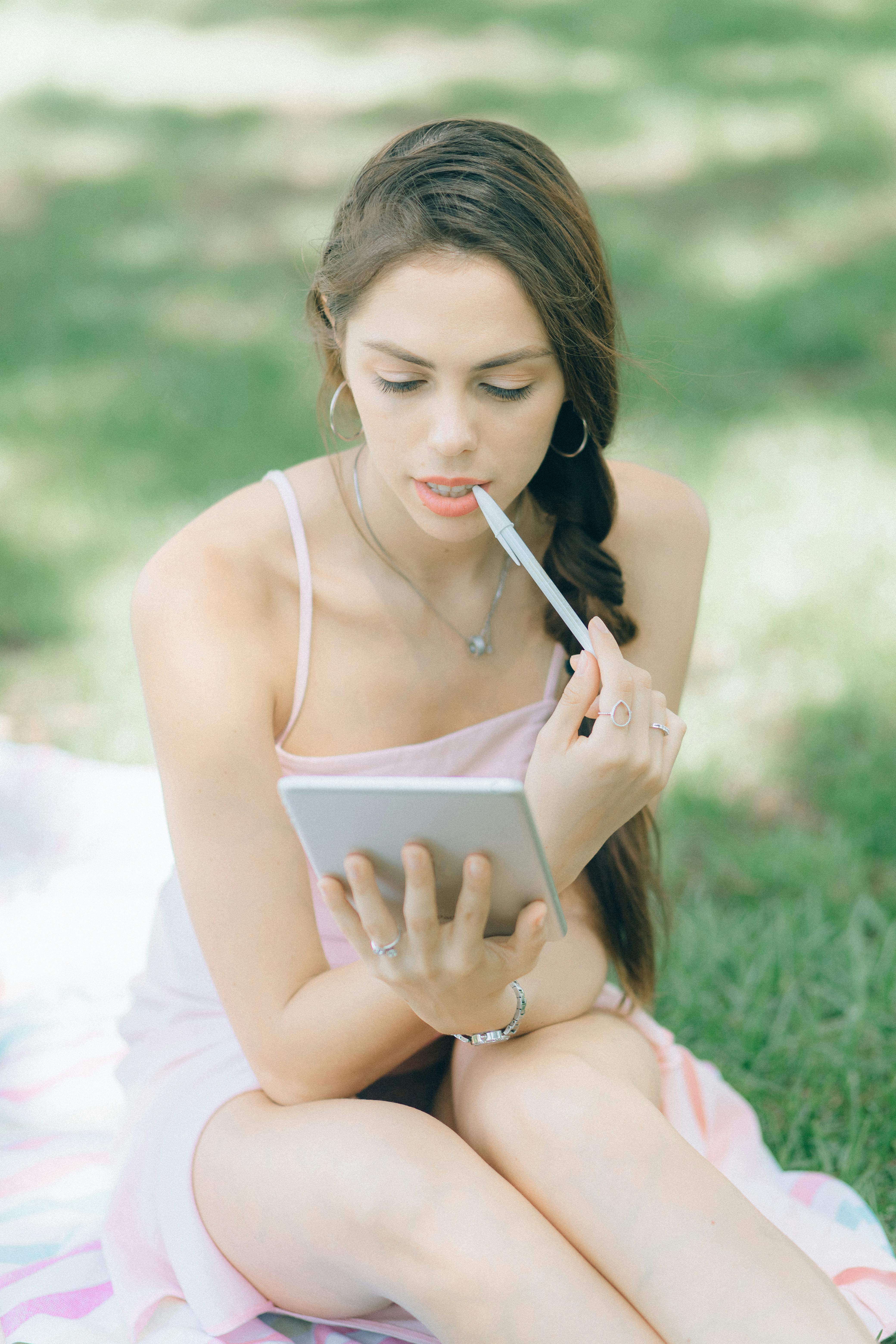 woman in black spaghetti strap top holding white tablet computer