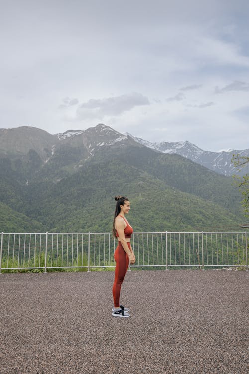 Woman in Red Brassiere and Leggings Standing Near Mountain 