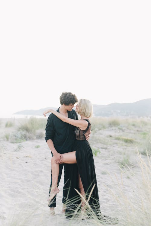 검은 티셔츠에 남자와 하얀 모래에 검은 드레스 키스 여자