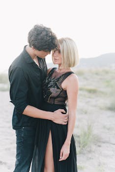 A couple embracing outdoors in stylish black clothing, evoking intimacy and romance.