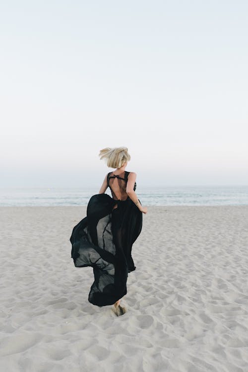 Vrouw In Zwarte Jurk Staande Op Het Strand